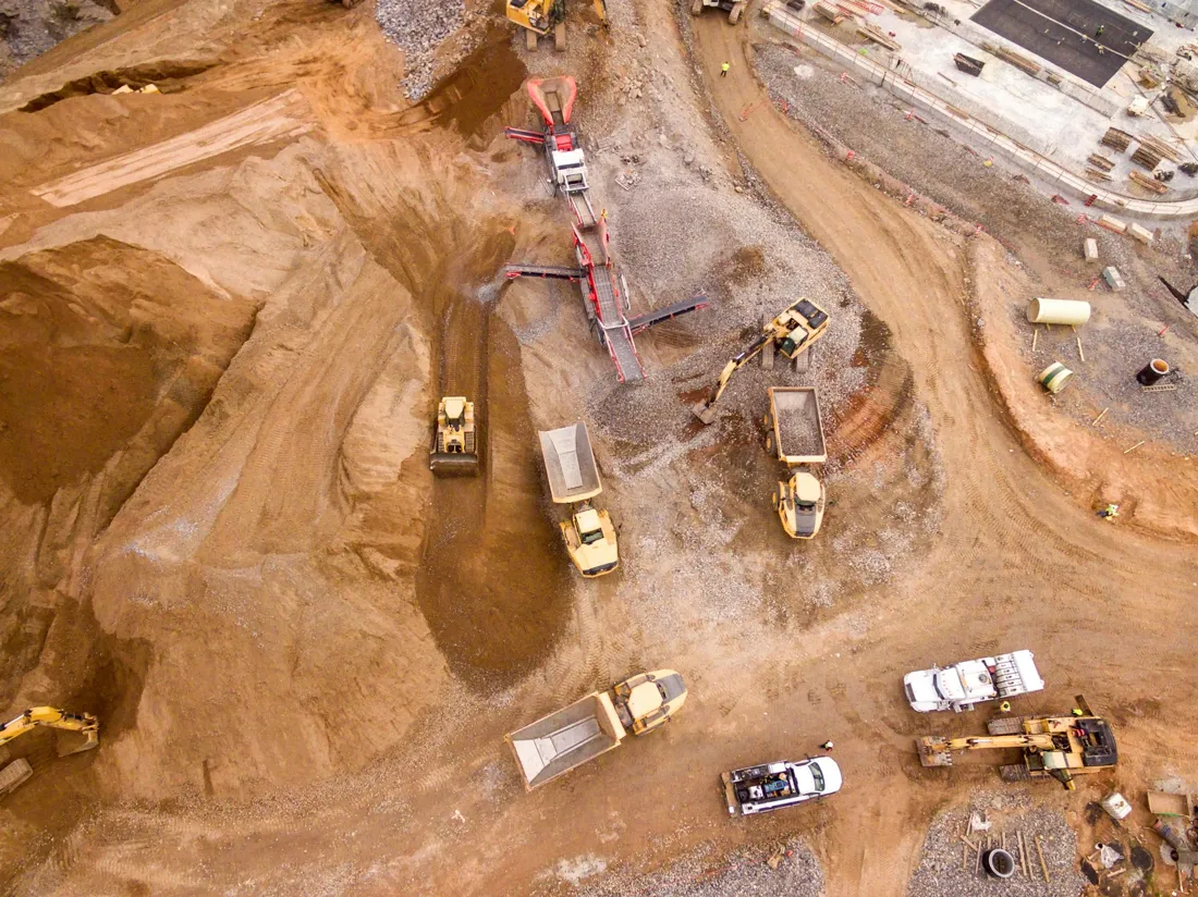 Aerial view of a mining operation with trucks, excavators and a mobile crusher